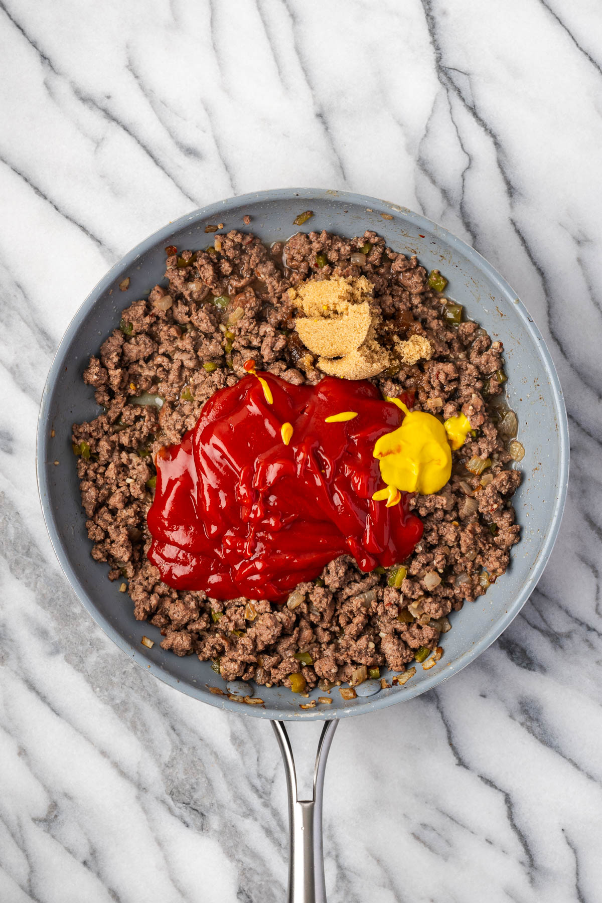 Ketchup, water, brown sugar and mustard added to the cooked ground beef in the skillet.