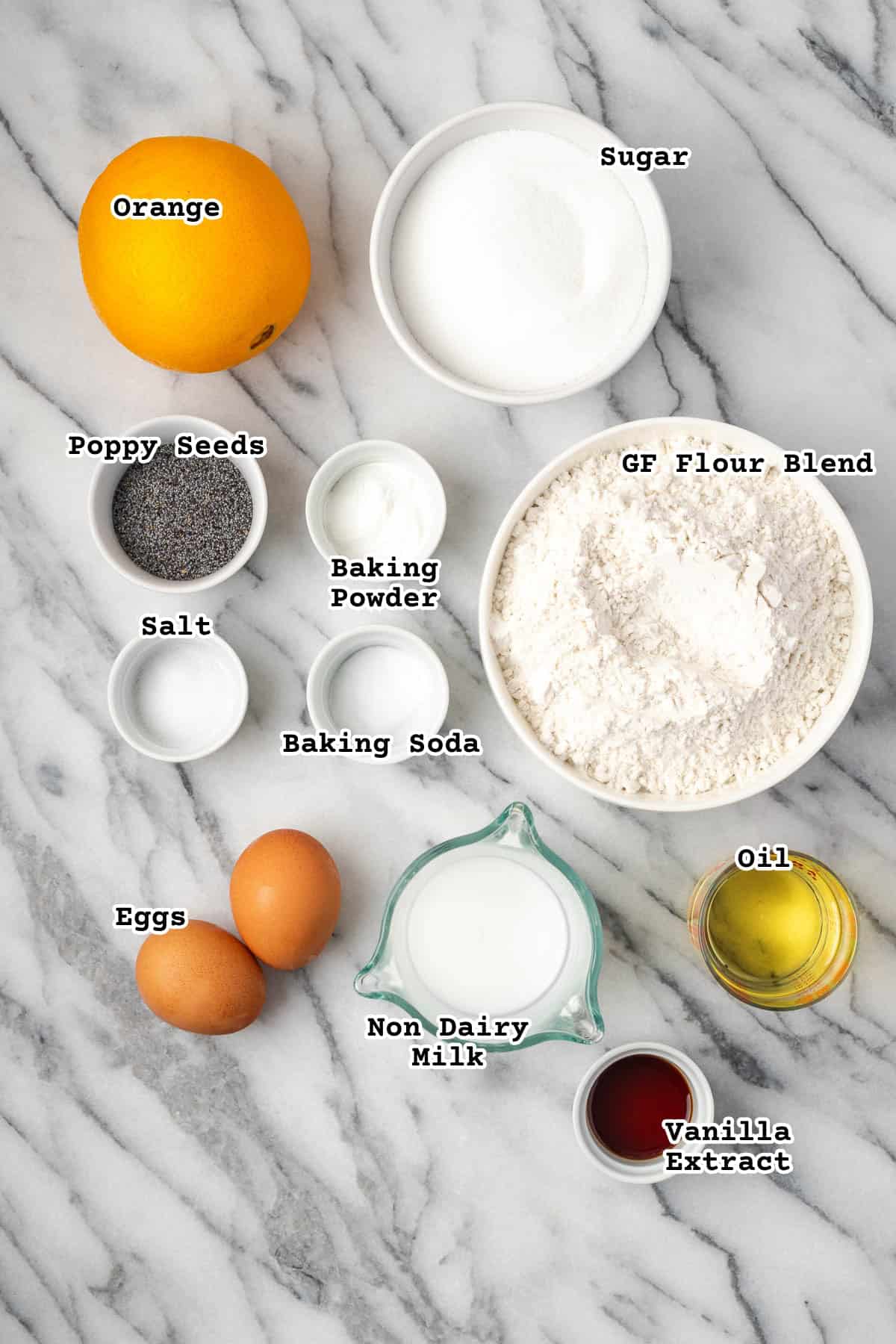 Ingredients for orange poppyseed muffins sitting on a marble counter.