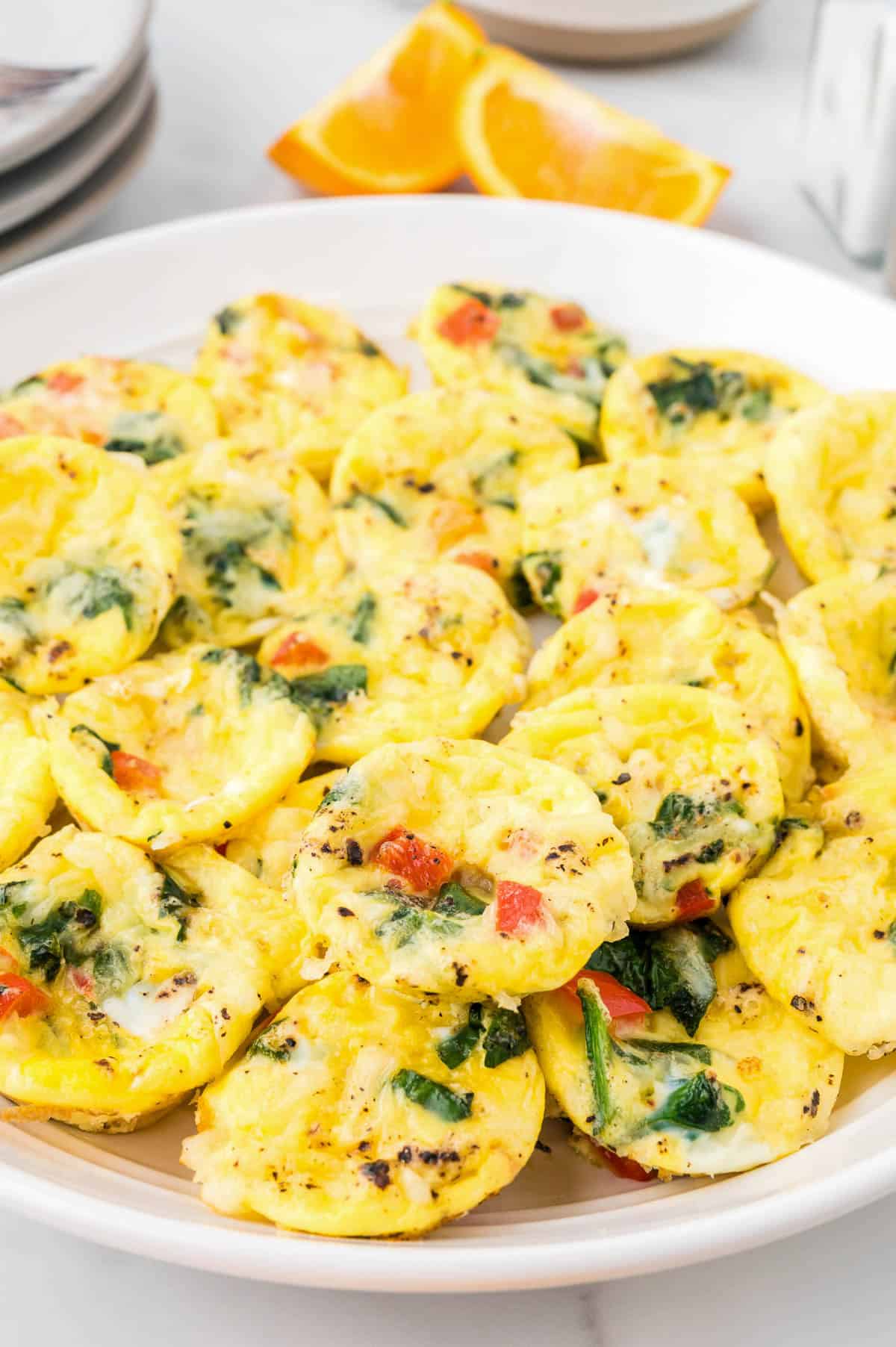 A bunch of egg bites sitting on a white serving plate.