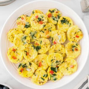 Several mini egg bites sitting on a large serving plate.
