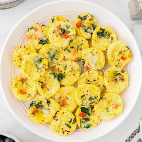 Several mini egg bites sitting on a large serving plate.