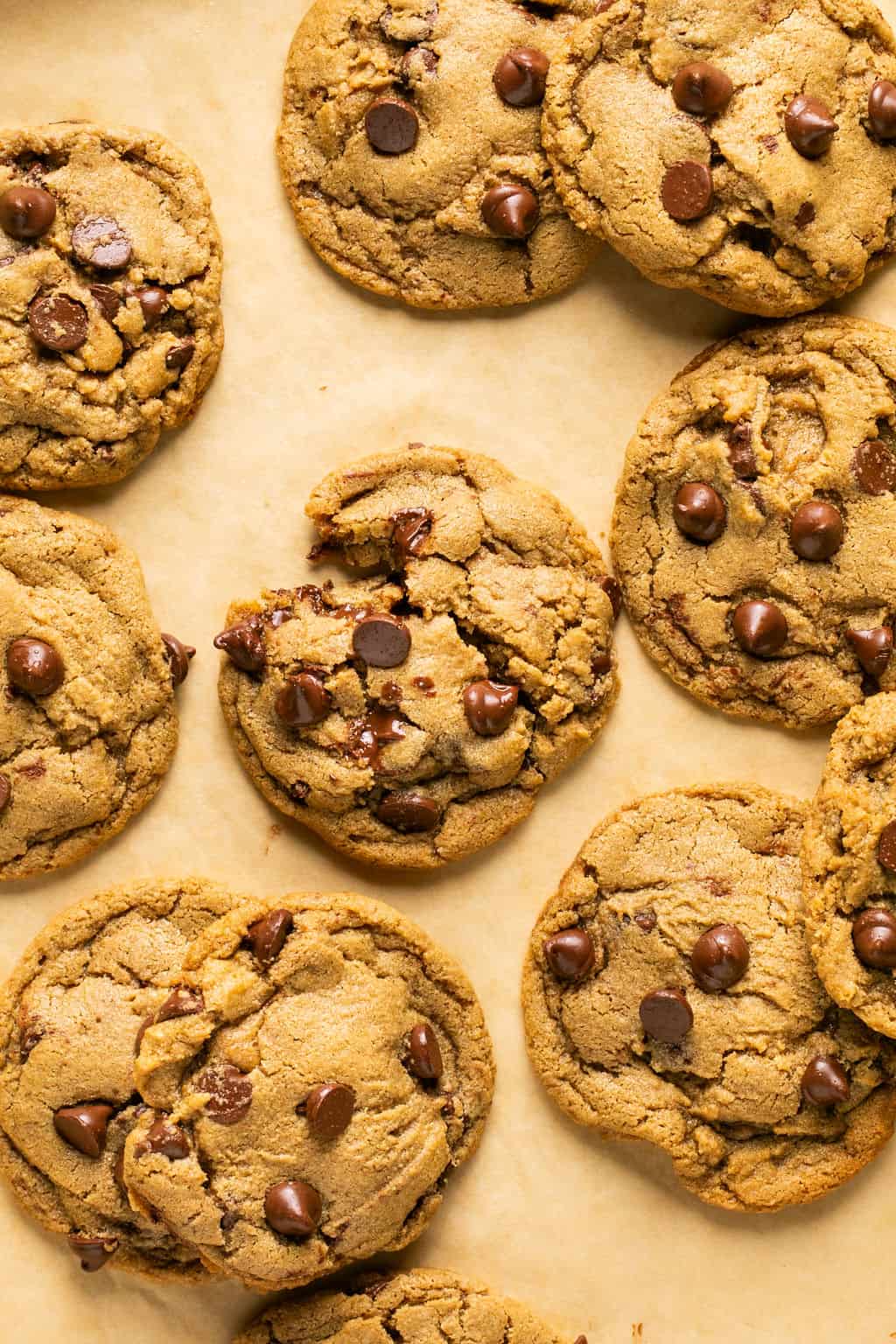 Several oat flour chocolate chip cookies scattered on a baking sheet.