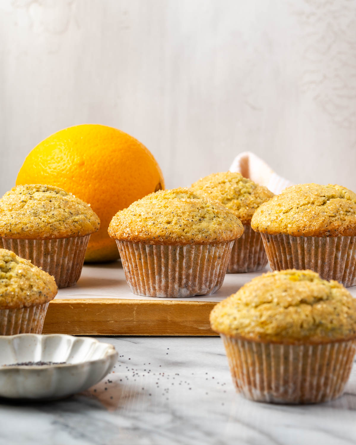 Several gluten free orange muffins sitting on a wood cutting board.