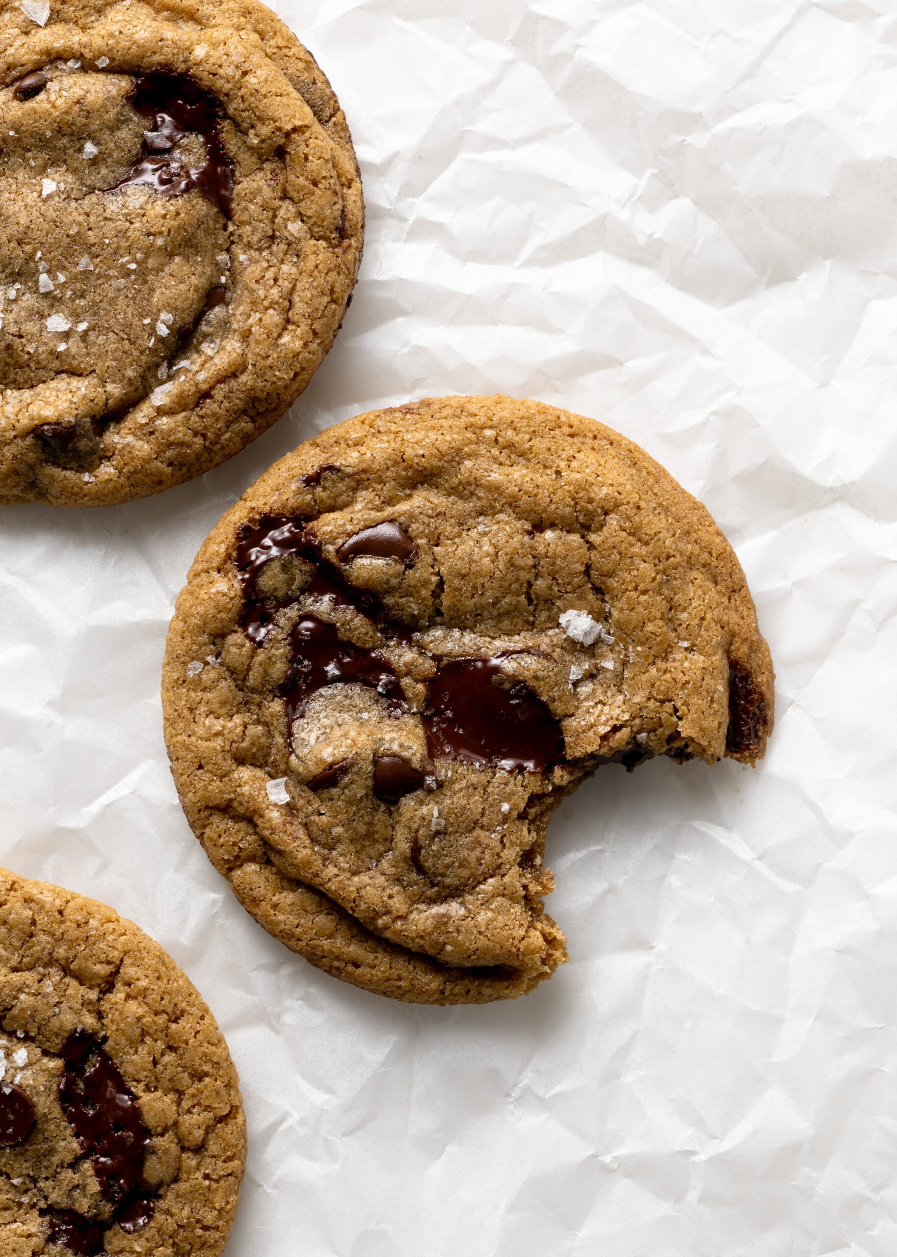 A single brown butter chocolate chip cookie with a bite taken out.