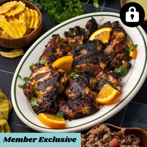 Grilled chicken thighs on a serving platter sitting on a tile counter.