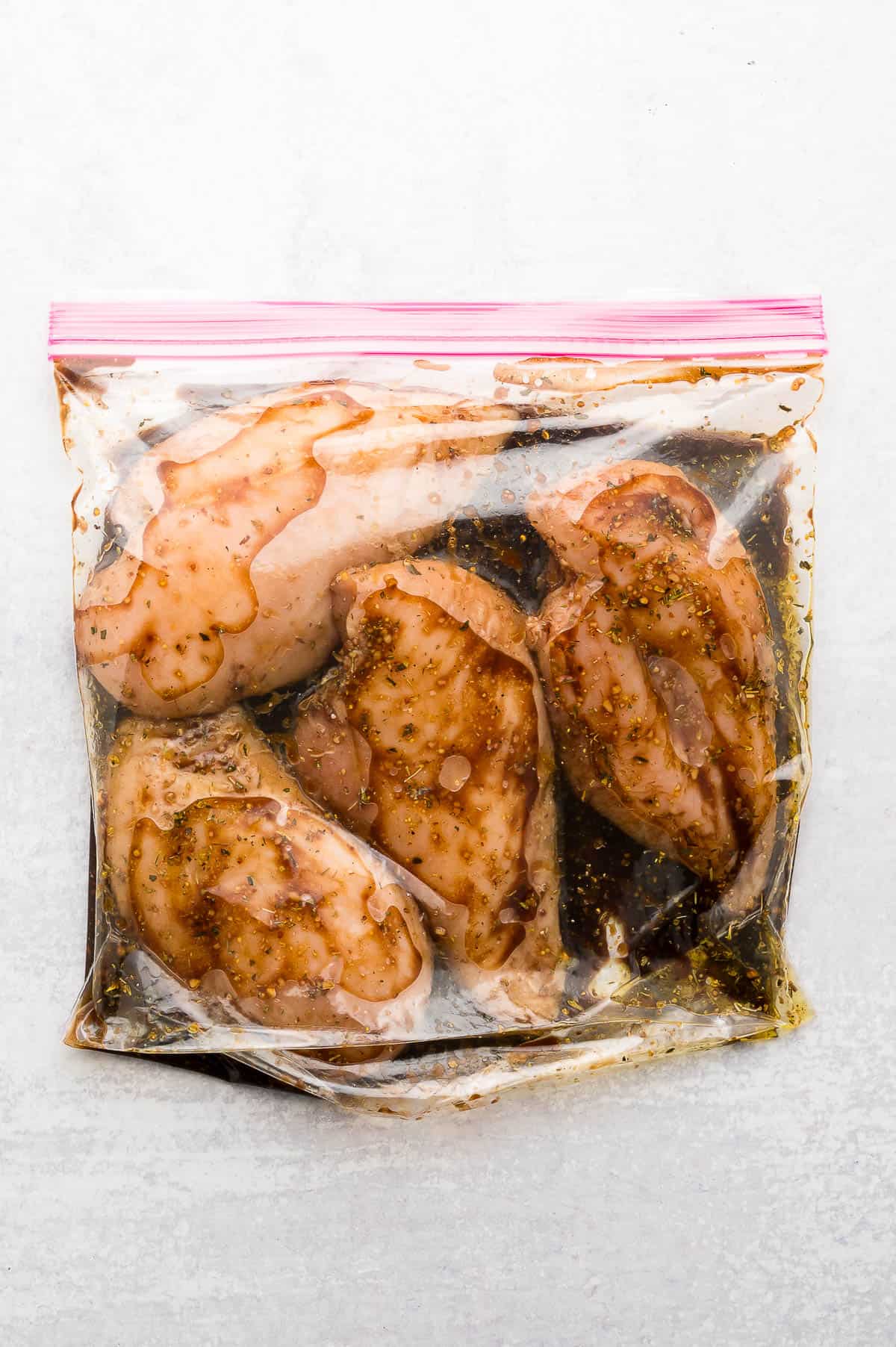 Raw chicken breasts with balsamic marinade in a large ziploc bag.