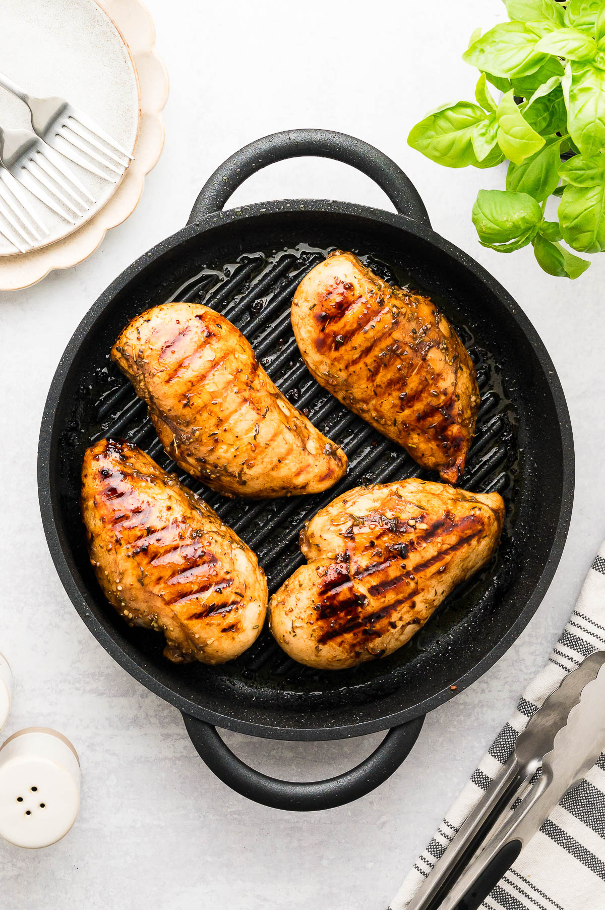 Four chicken breasts cooked in a stovetop grill pan.