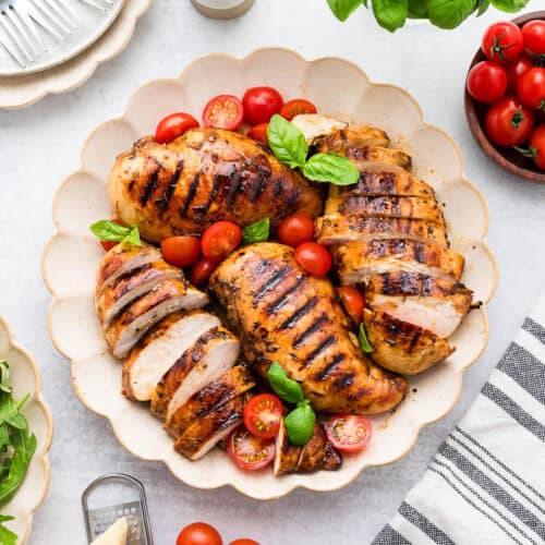 A serving tray with balsamic chicken, fresh basil and tomatoes.