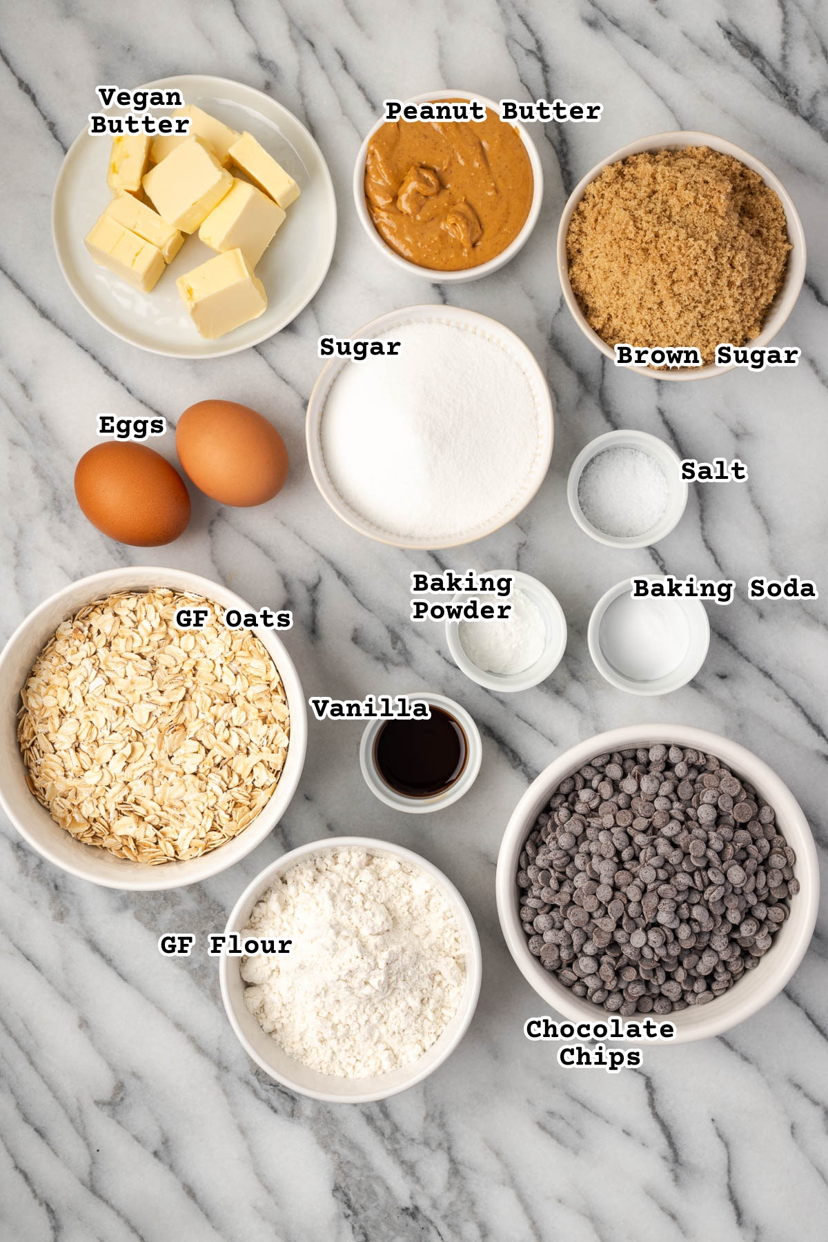 Ingredients for peanut butter oatmeal chocolate chip cookies on a marble counter.