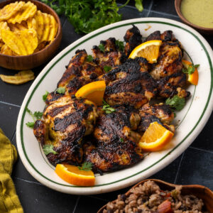A platter of grilled chicken thighs sitting on a tile counter.