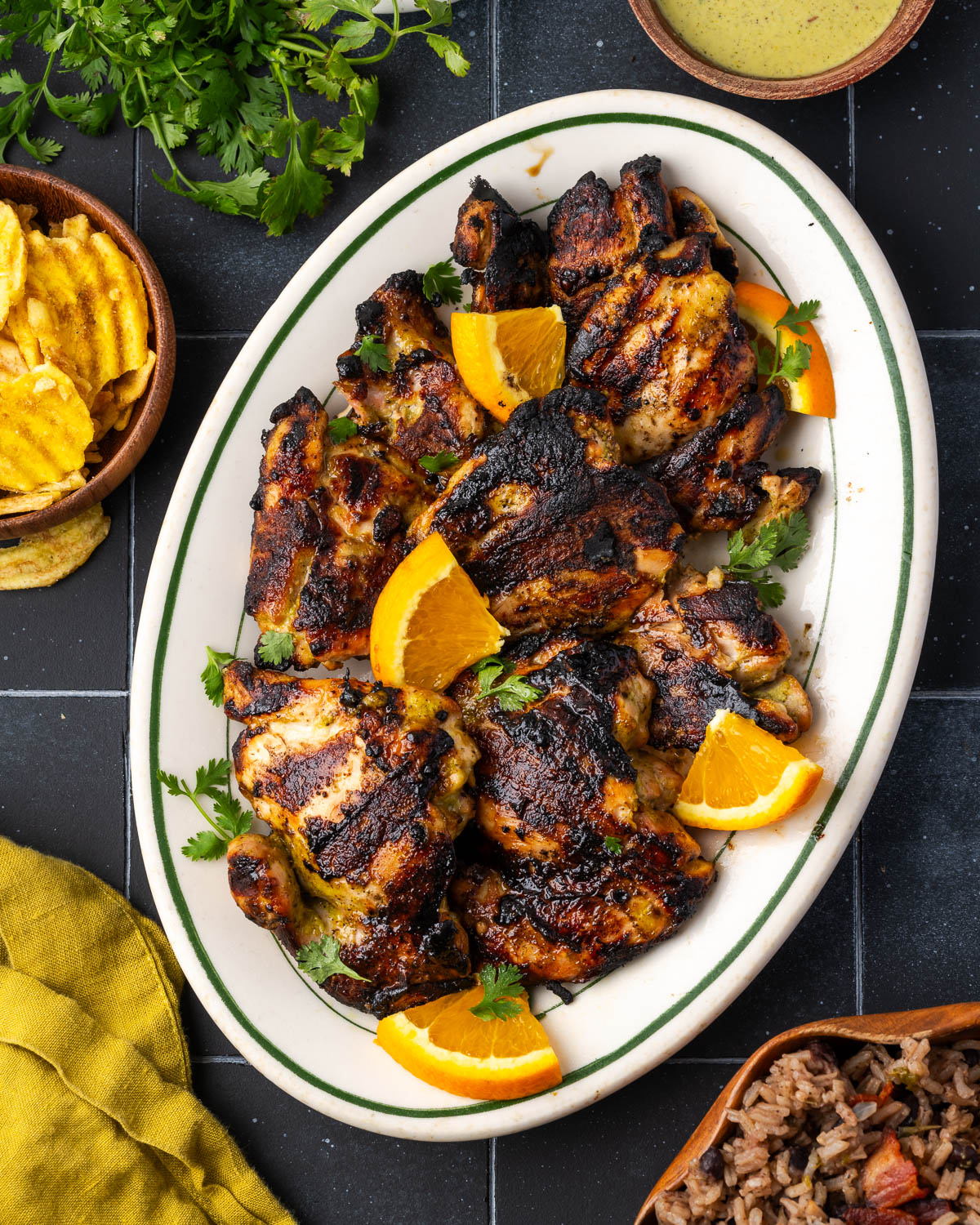 A plate of grilled chicken thighs sitting on a dark tile countertop. 
