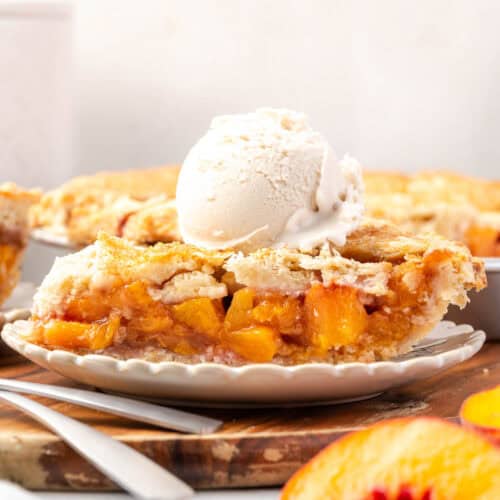A slice of peach pie topped with vanilla ice cream sitting on a small dessert plate.