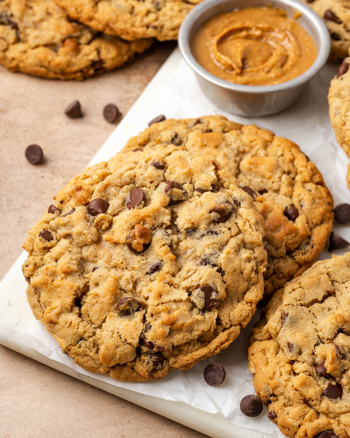 Several peanut butter oatmeal chocolate chip cookies on a marble board.