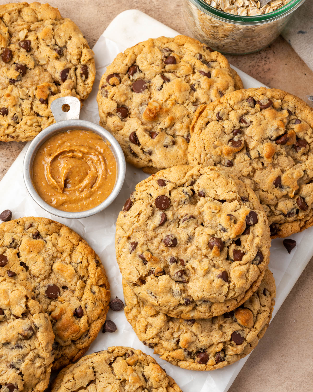 Several peanut butter oatmeal chocolate chip cookies scattered on a marble tray.