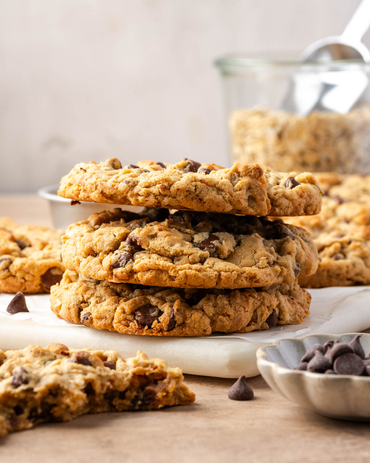 Three peanut butter oatmeal chocolate chip cookies stacked on a marble tray.